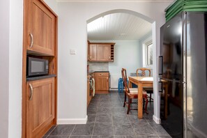 A kitchen with wooden cabinets, a stainless steel refrigerator, a microwave, and a dining area with a table and chairs.
