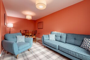 A living room with two sofas, a coffee table, and a dining table.
