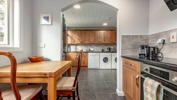 A modern kitchen with wooden cabinets, a dishwasher, a washing machine, and a coffee maker.
