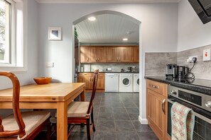 A modern kitchen with wooden cabinets, a dishwasher, a washing machine, and a coffee maker.