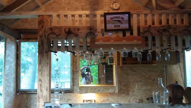 A rustic wooden interior with a bar area, wooden beams, and a clock on the wall.