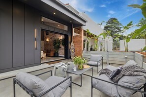 An outdoor patio with modern furniture, a brick wall, and potted plants.