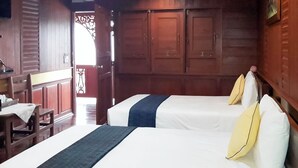 Ein Zimmer mit zwei Betten, Holzmöbeln und Blick ins Freie.