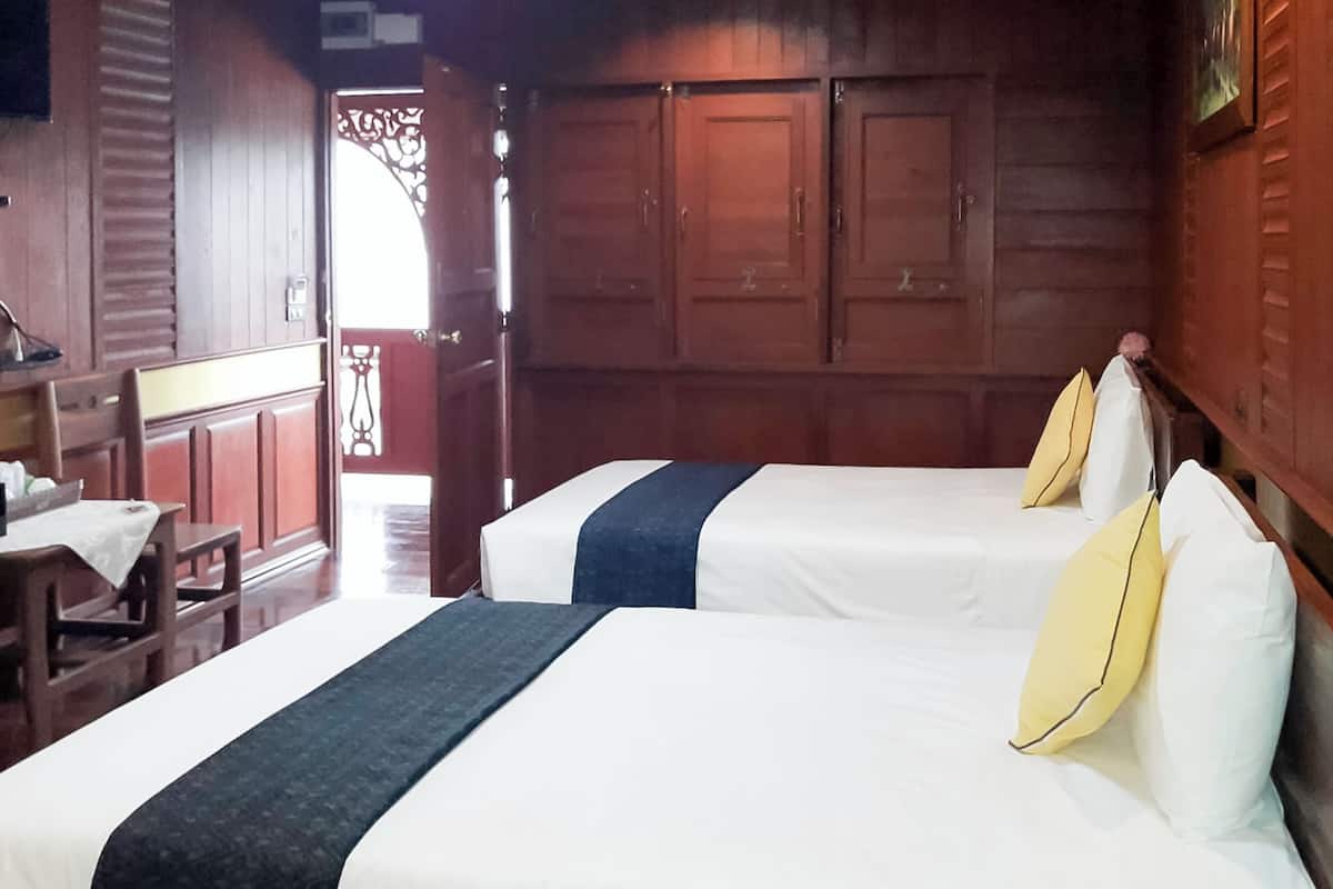 Una habitación con dos camas, muebles de madera y vistas al exterior.