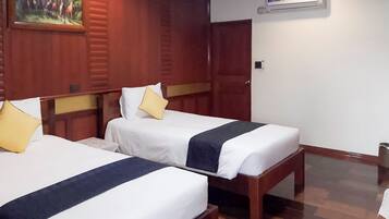 Une chambre d’hôtel avec deux lits, des têtes de lit en bois, du linge de lit blanc et un tableau au mur.