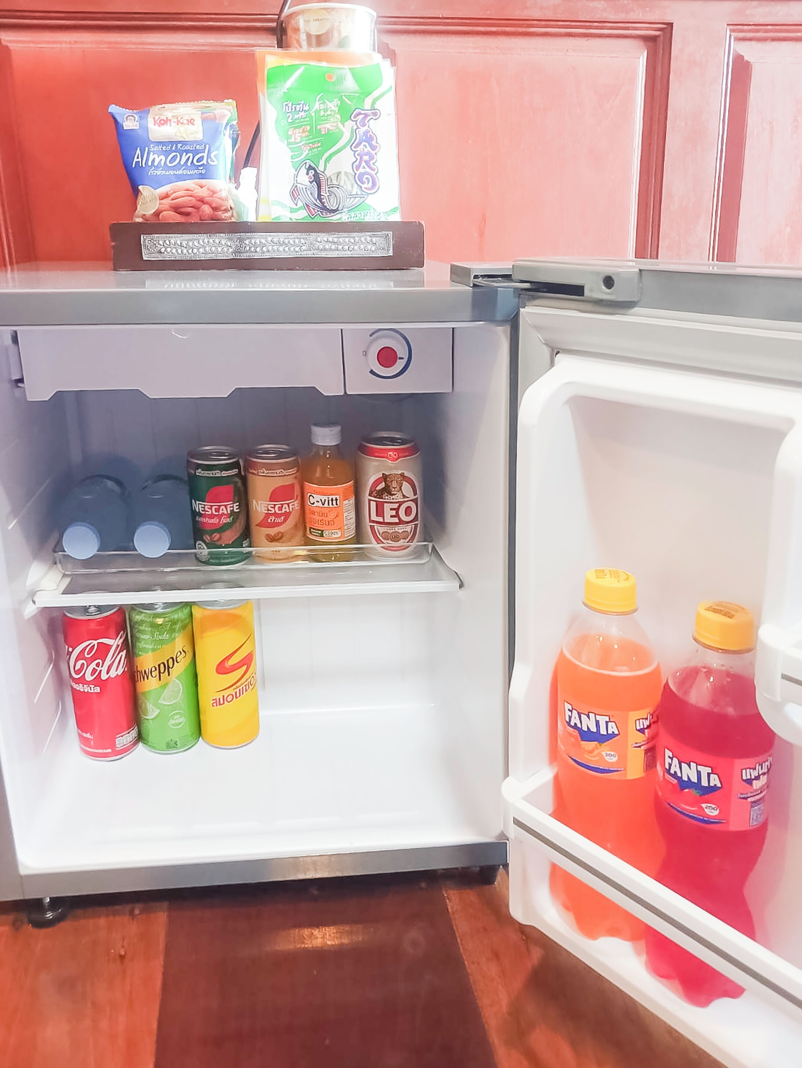 Un refrigerador lleno de diversas bebidas, incluyendo latas y botellas de refresco.