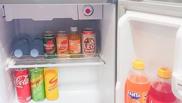 Un refrigerador lleno de diversas bebidas, incluyendo latas y botellas de refresco.