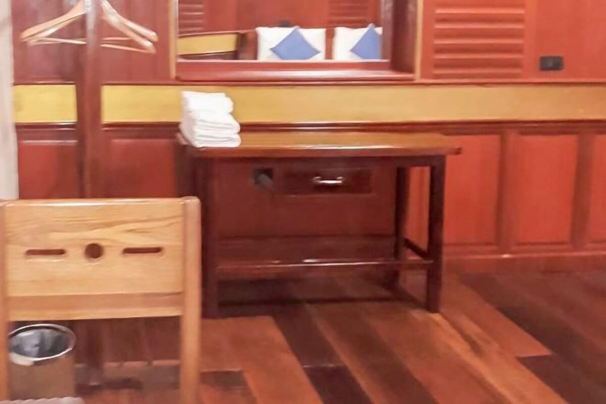 Une pièce en bois avec une petite table et une chaise, un miroir et une fenêtre avec des stores.