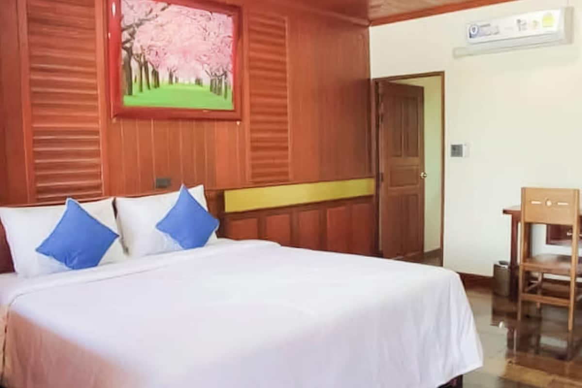 Habitación de hotel con una cama grande, paneles de madera en las paredes, un cuadro de flores de cerezo y un escritorio con una silla.