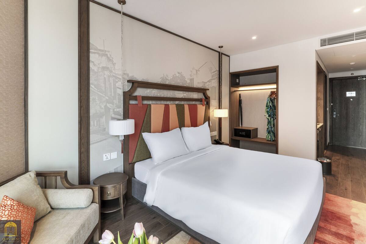Ein modernes Hotelzimmer mit einem großen Bett, einem Sofa, einem Nachttisch und einem Spiegel.