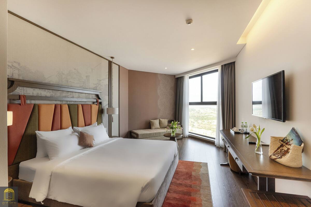 Ein modernes Hotelzimmer mit einem großen Bett, einer Couch, einem Schreibtisch und einem Fernseher.