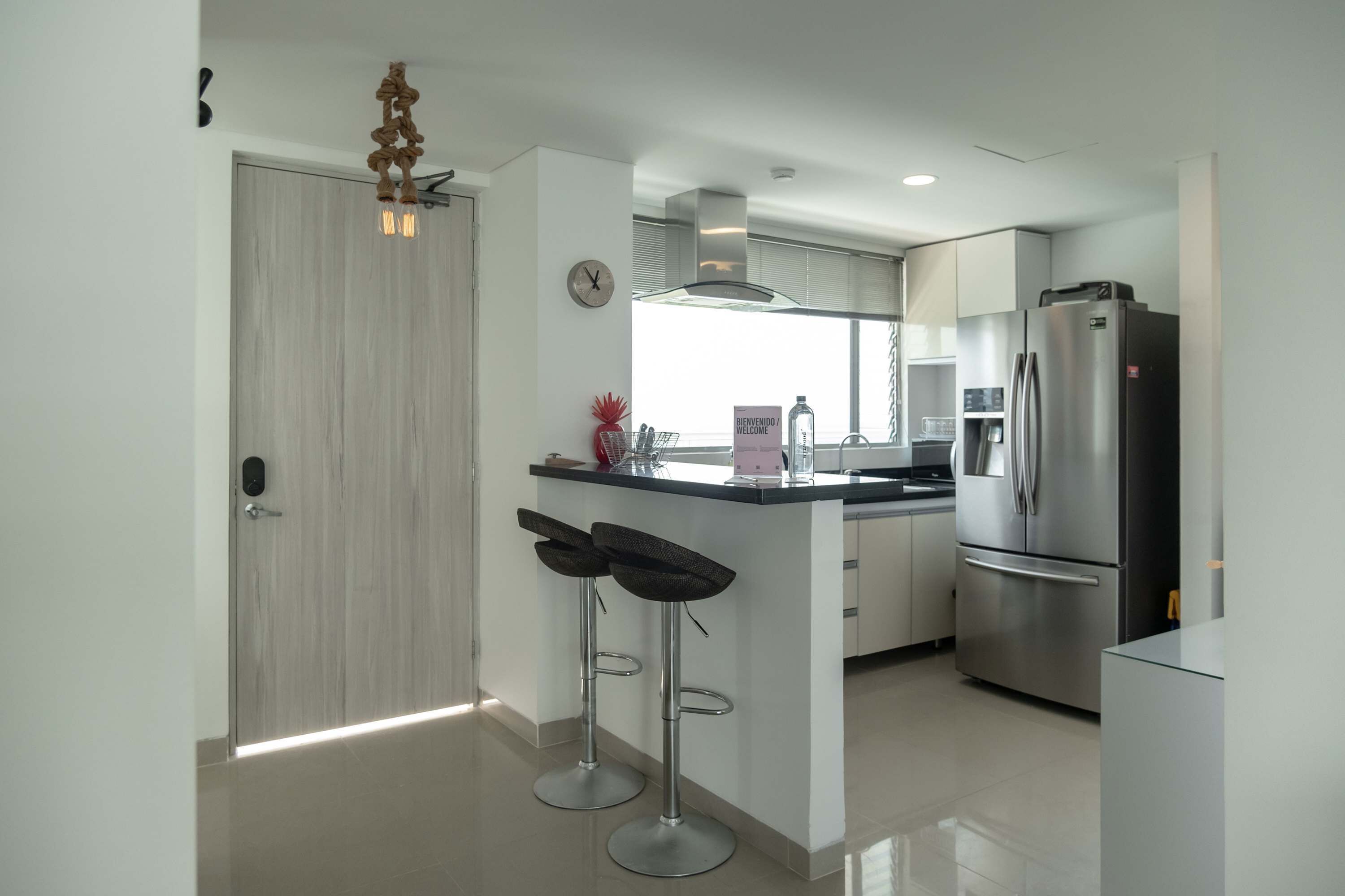 A modern kitchen with a central island, stainless steel appliances, and two bar stools.