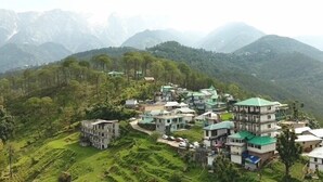 A cluster of traditional houses with green roofs, terraced fields, and a mountainous backdrop. - The Unmad Satovari (Dharamshala)