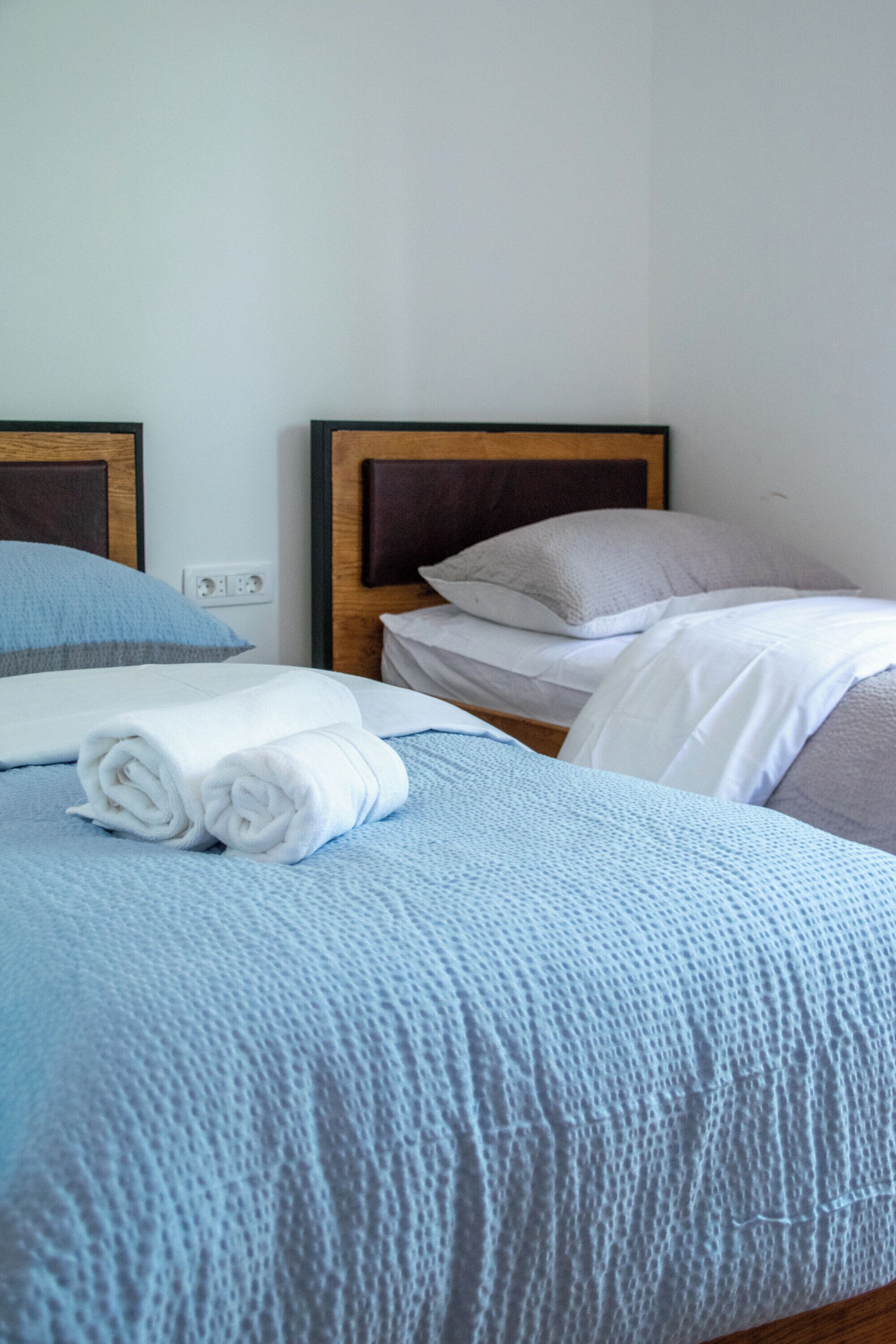 Un lit bien fait, avec une couvre-lit bleue, des oreillers blancs et une serviette blanche enroulée.