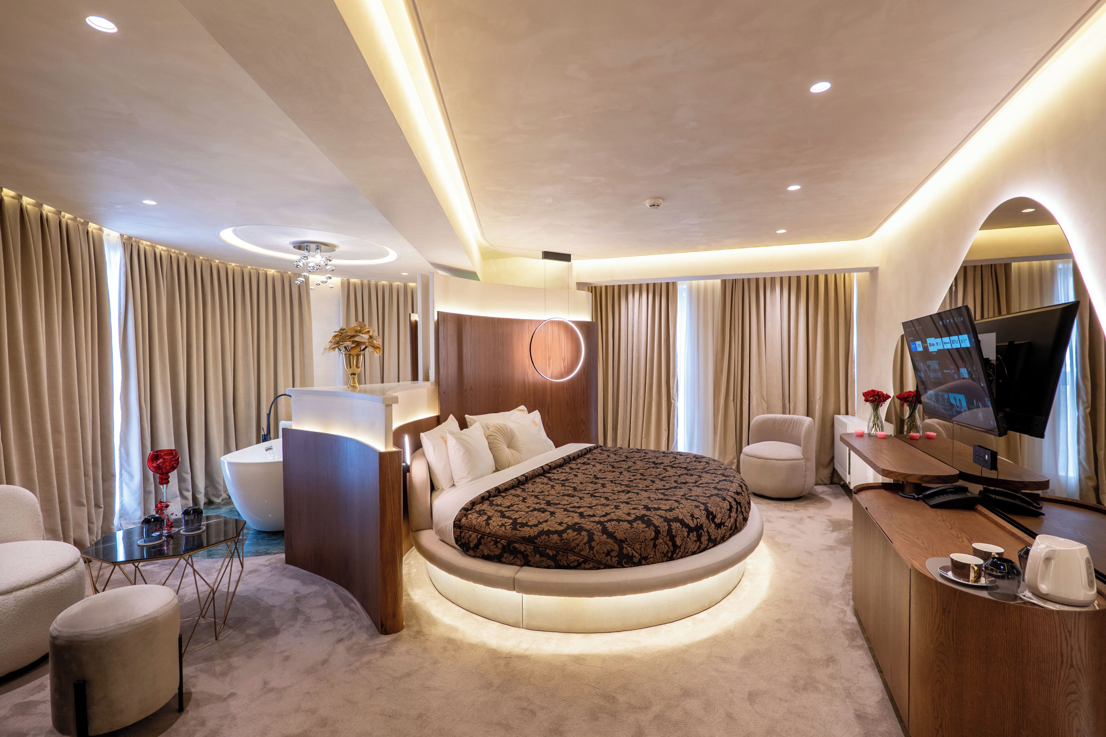 A modern hotel room with a large bed, a desk, a television, and a bathroom.