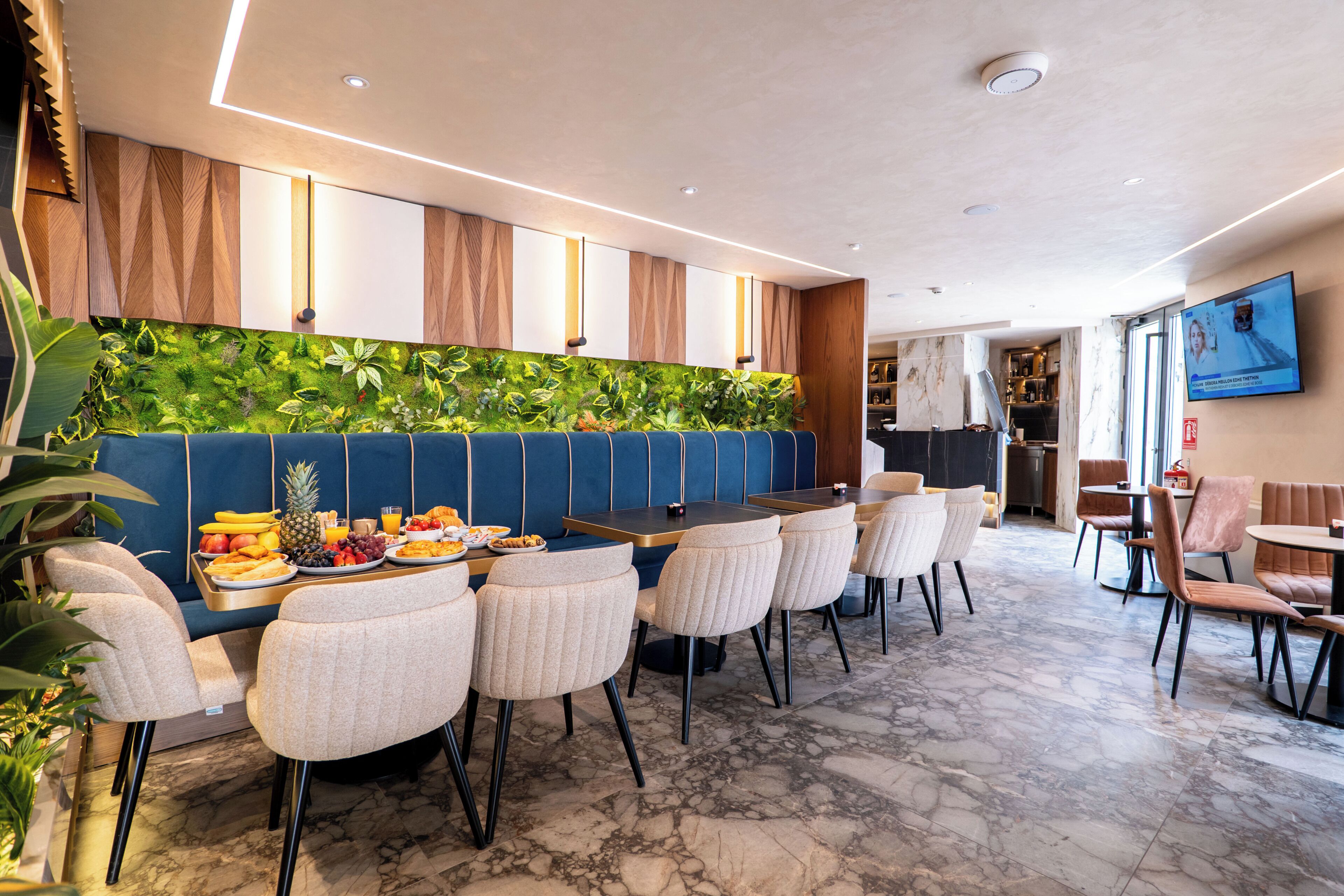 A modern hotel lobby with a bar area, seating, and a television screen.