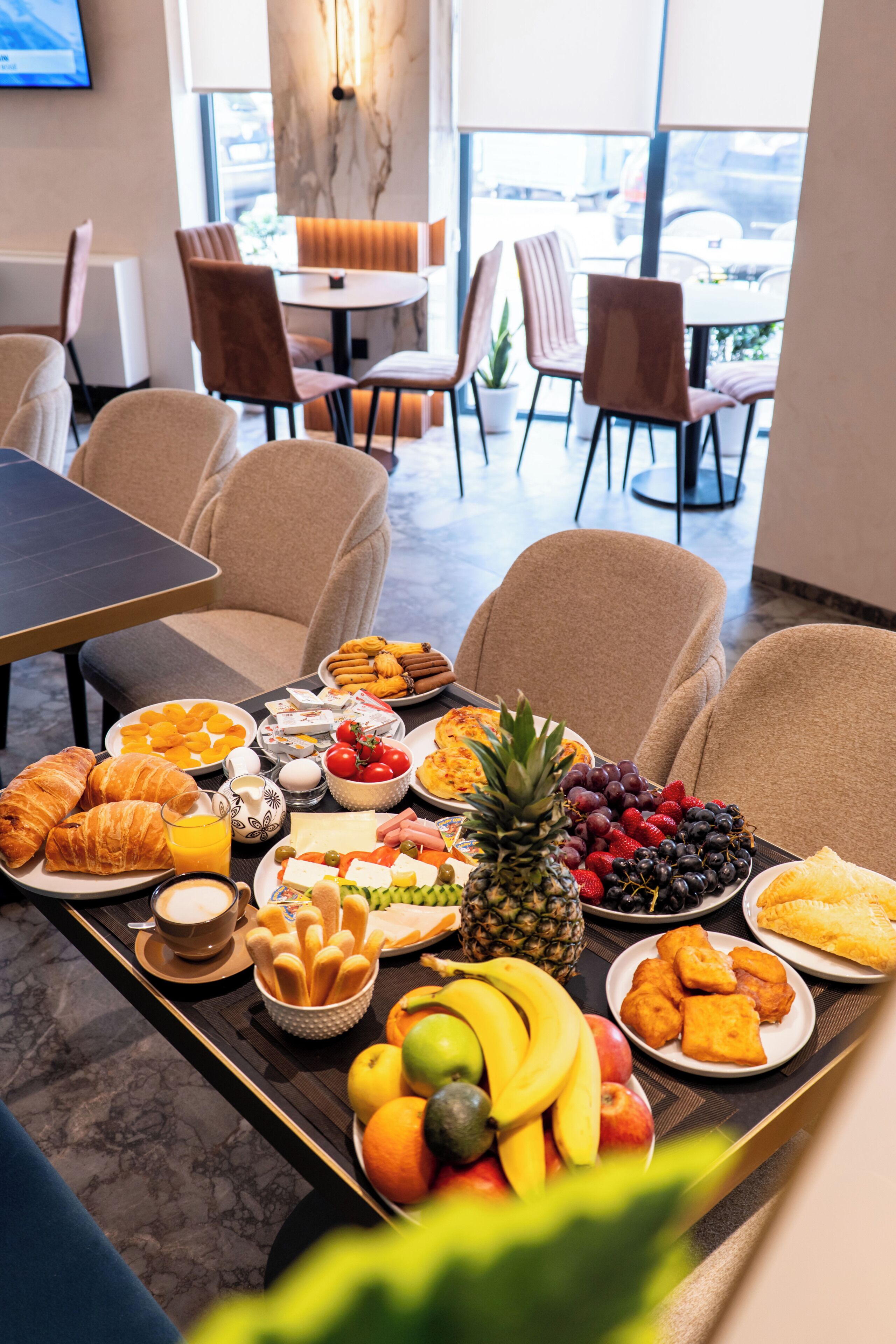 Un bufé de desayuno con diversas frutas, pasteles y bebidas.