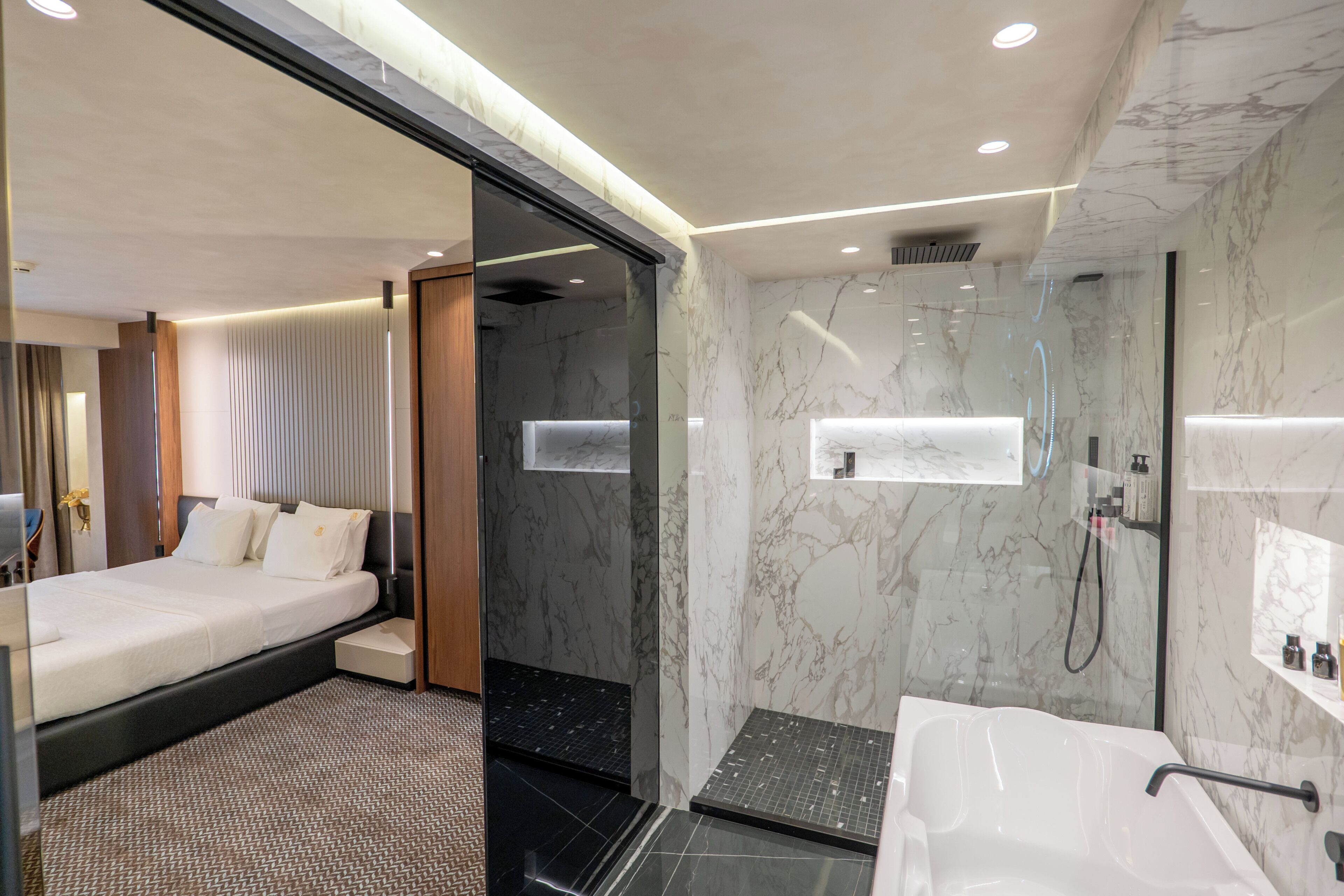 Een moderne hotelkamer met een bed, een douche en een badkamer met bad en wastafel.