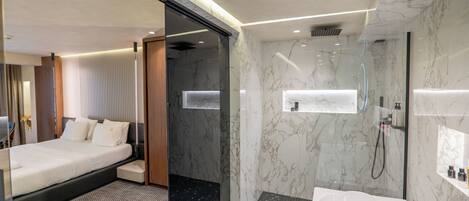 A modern hotel room with a bed, a shower, and a bathroom with a bathtub and vanity.