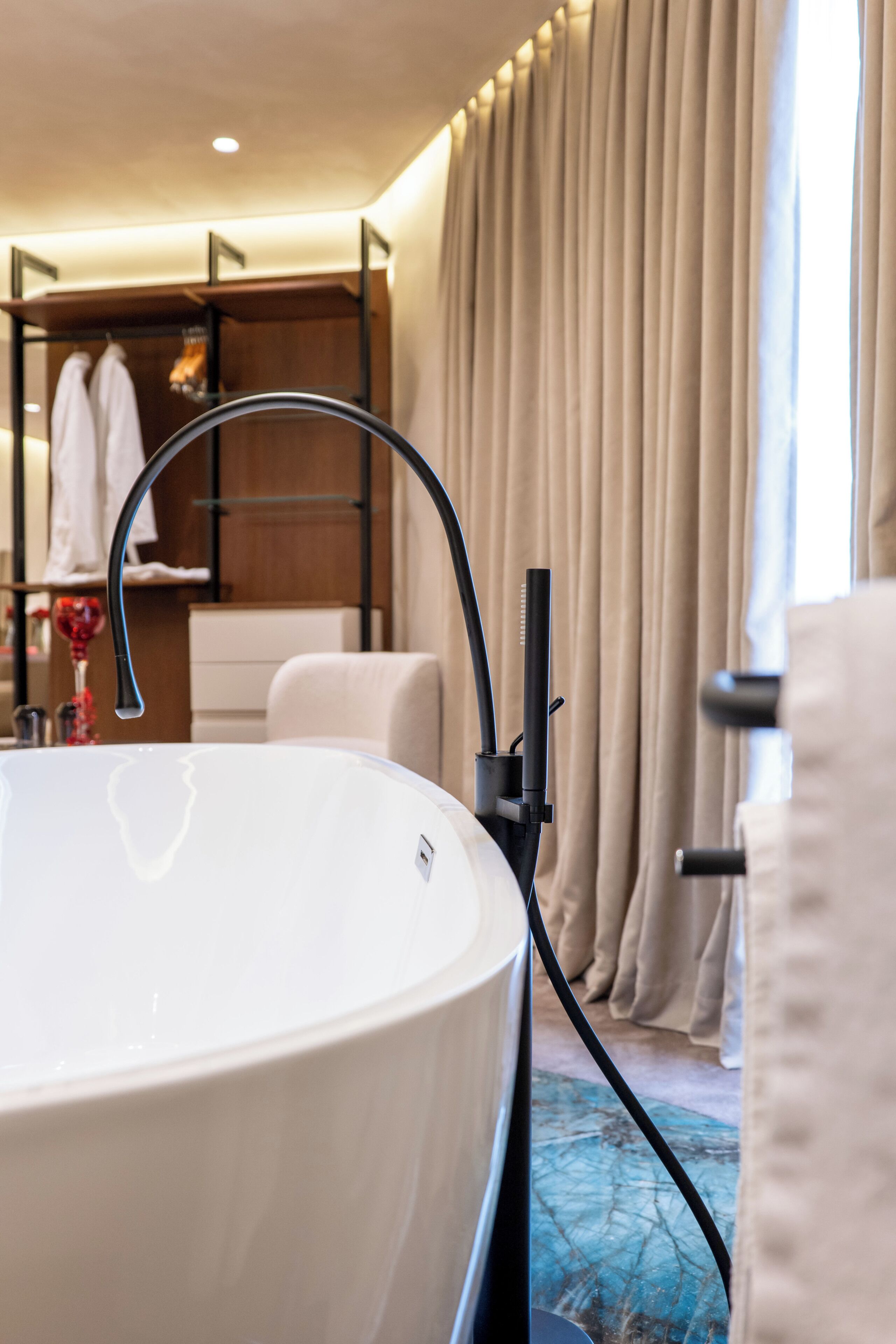 A modern bathroom with a large bathtub, a towel rack, and a shower area.