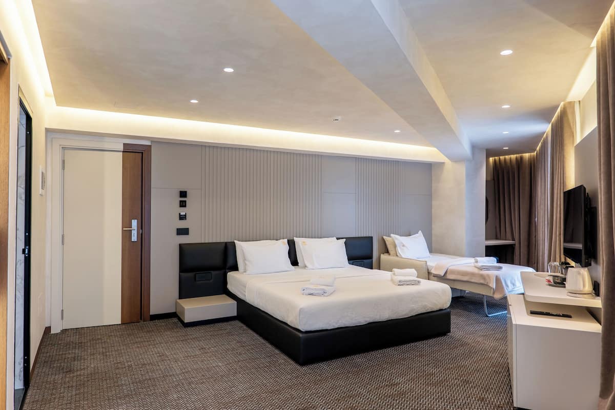 A modern hotel room with a large bed, bedside tables, a desk, and a television.