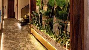 A hallway with a marble floor, wooden paneling, and a plant display. - Mattis Hotel (Tirana)