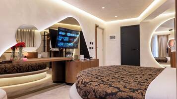 Una habitación de hotel moderna con una cama curvada, televisión, escritorio y espejo.