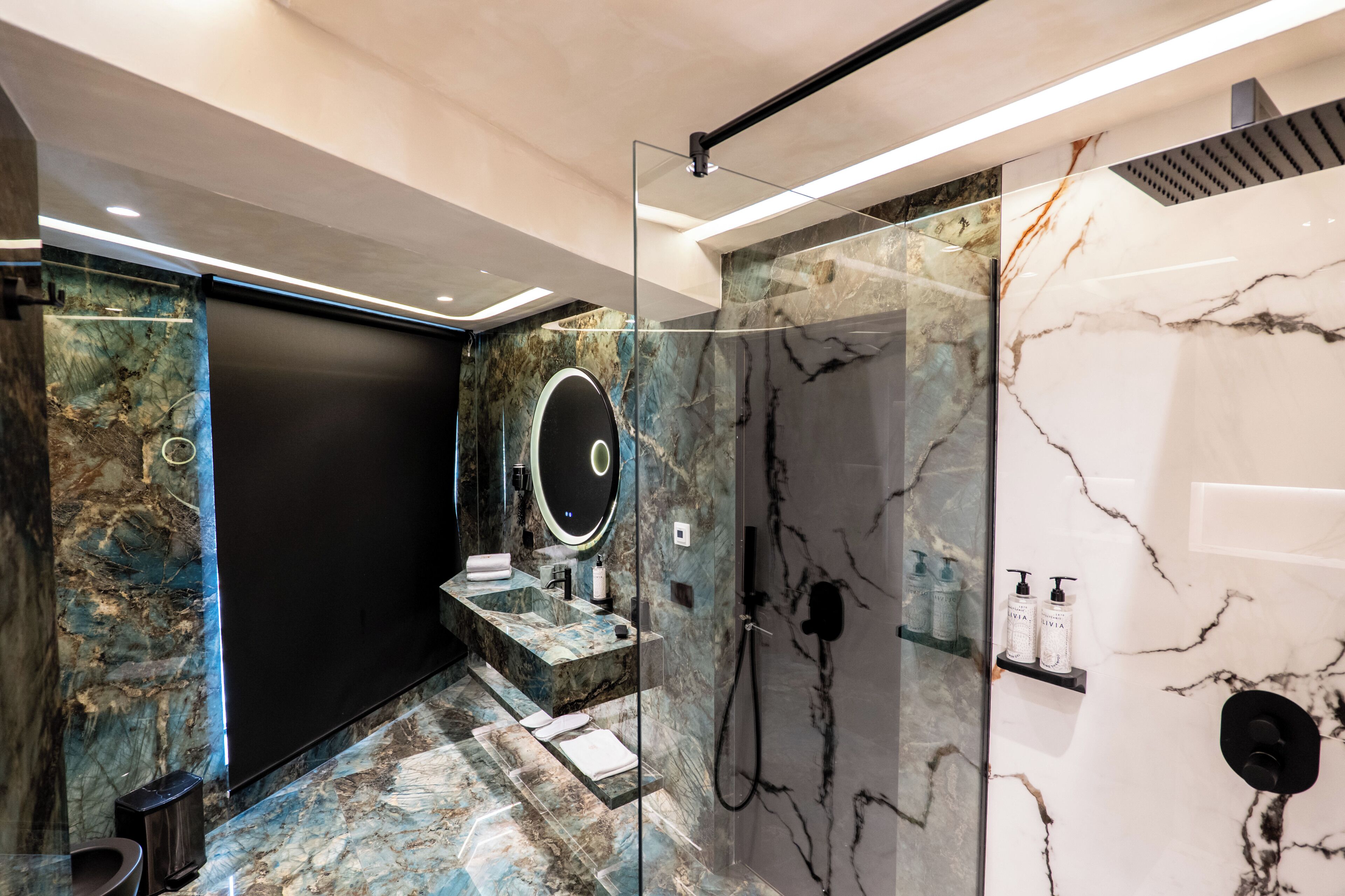 A modern bathroom with a marble vanity, a glass-enclosed shower, and a large mirror.