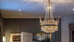Un comedor con una mesa de madera oscura, sillas ornamentadas y una lámpara de cristal.