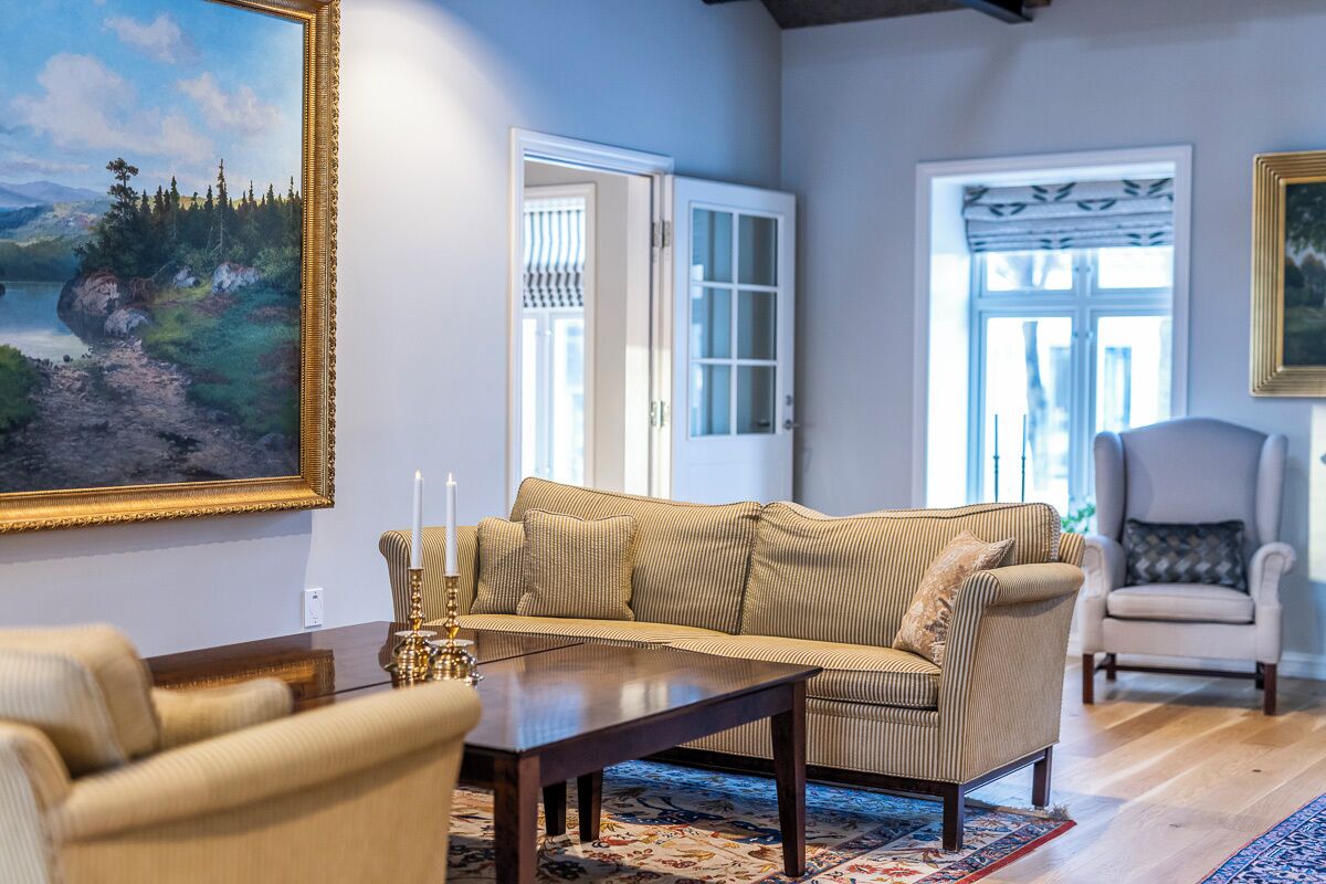 A living room with a sofa, armchairs, a coffee table, and a painting on the wall.