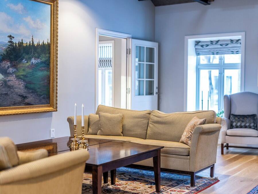 A living room with a sofa, armchairs, a coffee table, and a painting on the wall.