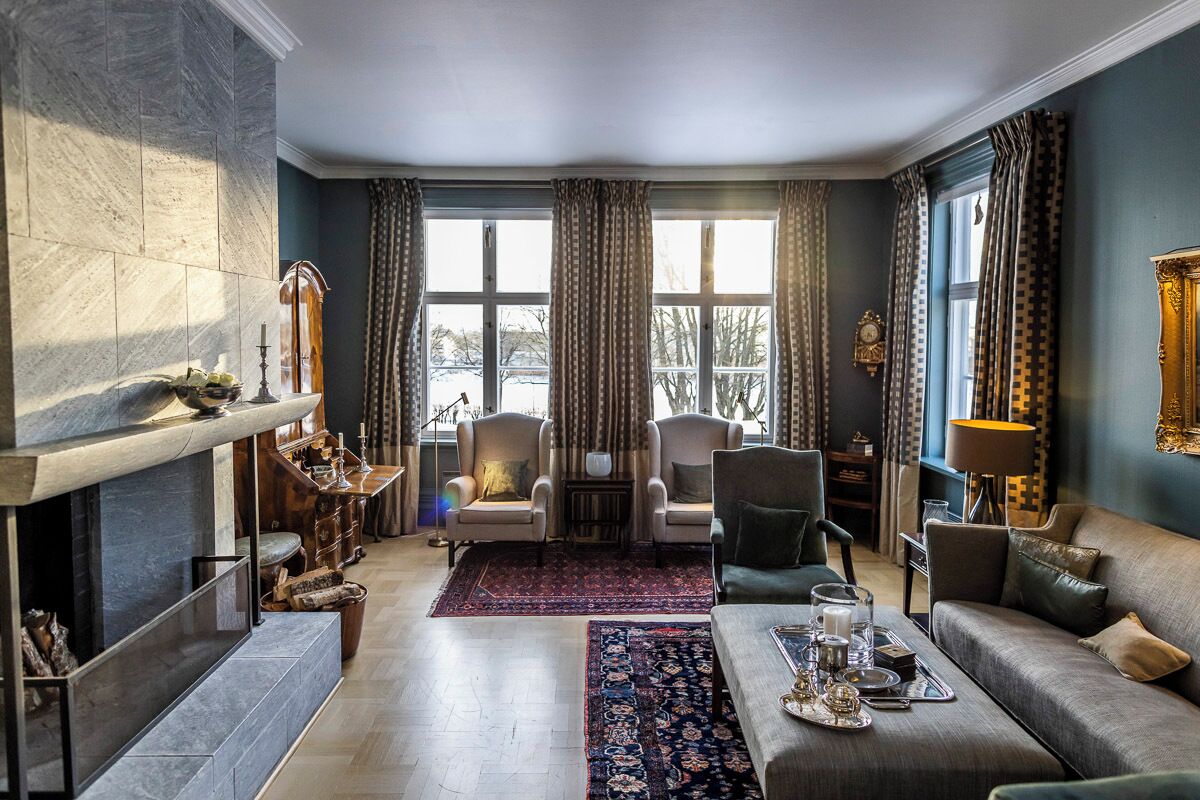 A spacious living room with a fireplace, two armchairs, a sofa, and a coffee table.