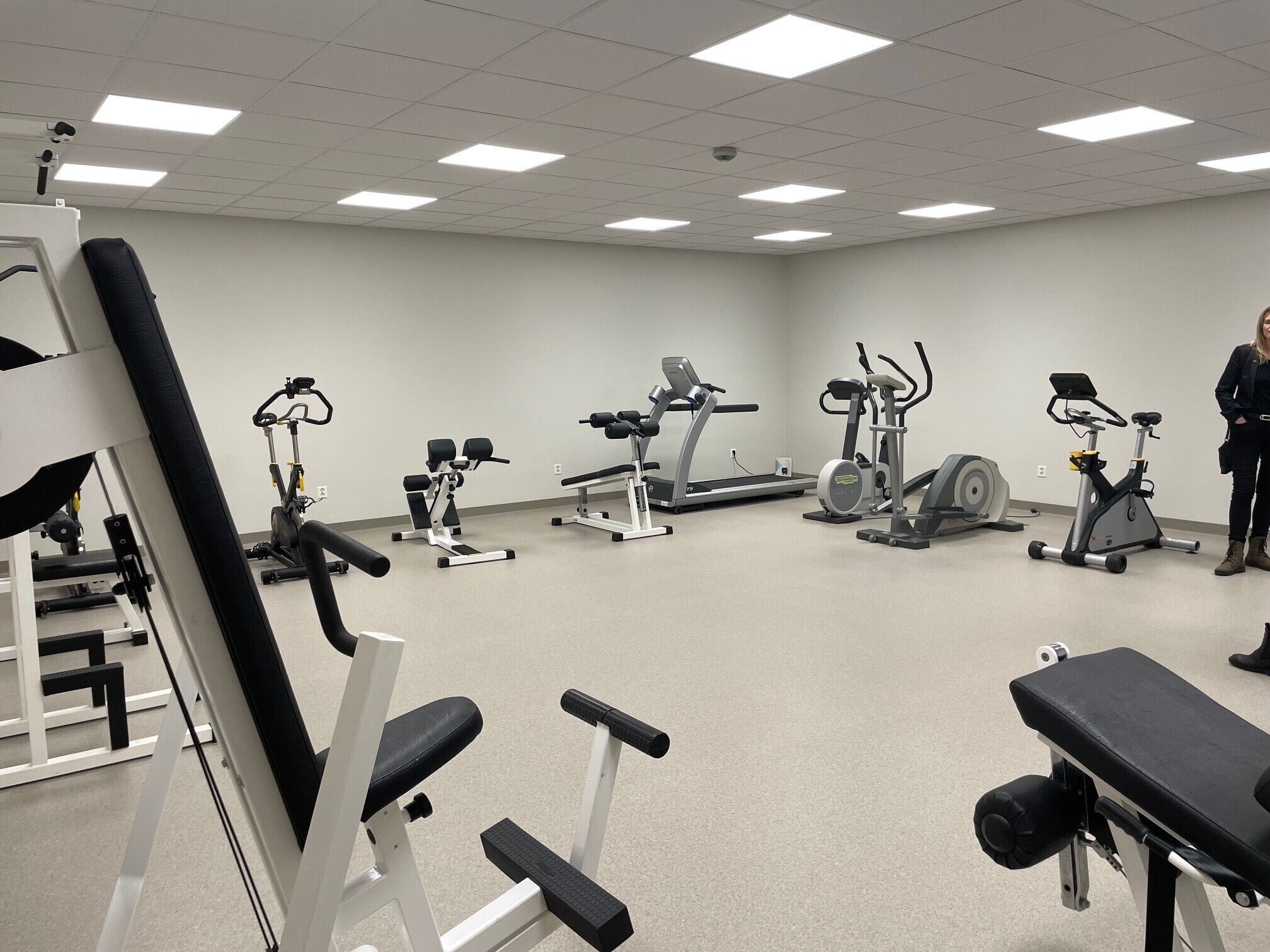 Een sportschool met diverse fitnessapparaten, waaronder loopbanden, elliptische trainers en krachtapparaten.