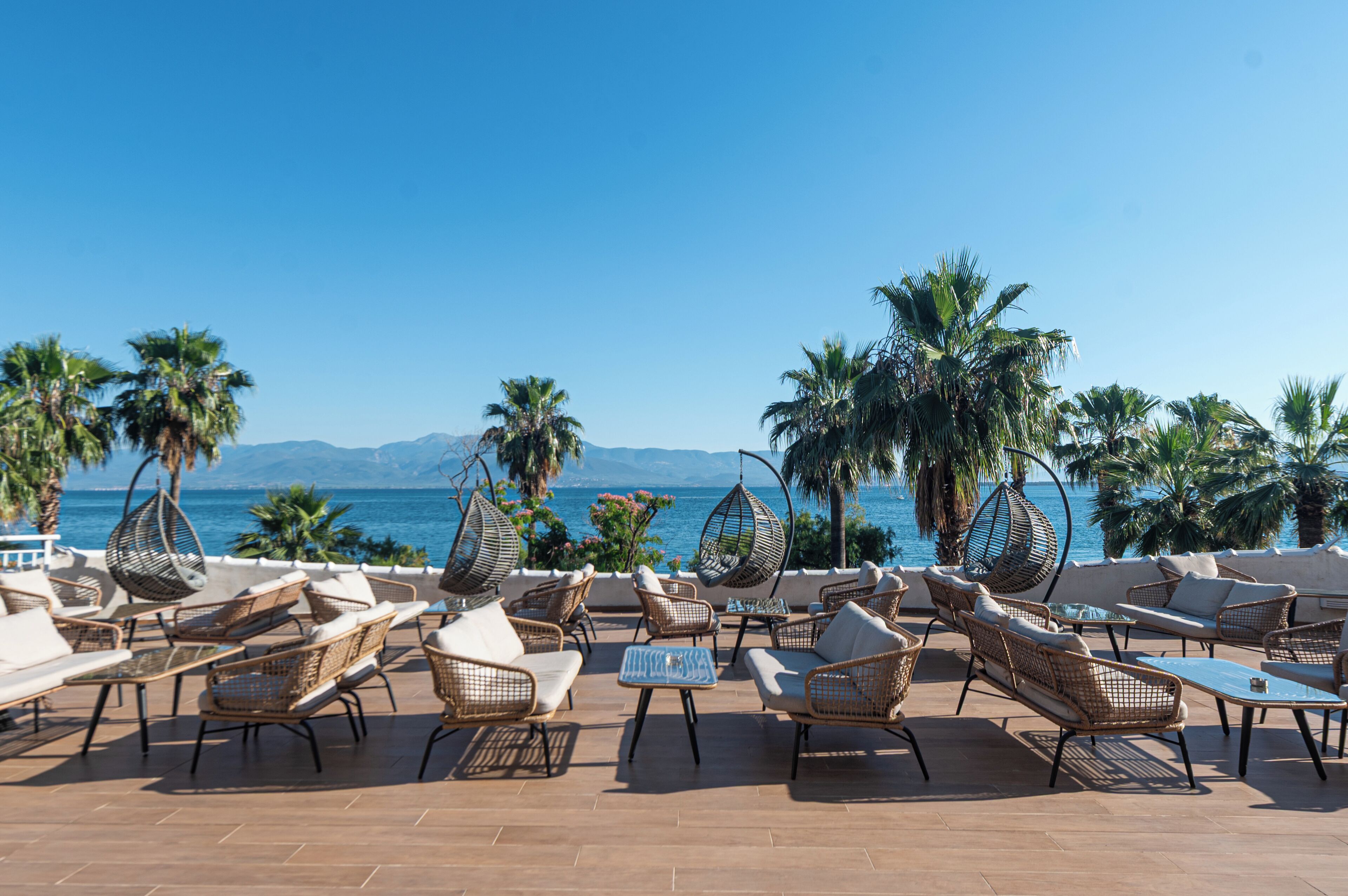 Una terraza con mobiliario de mimbre y vista al mar.