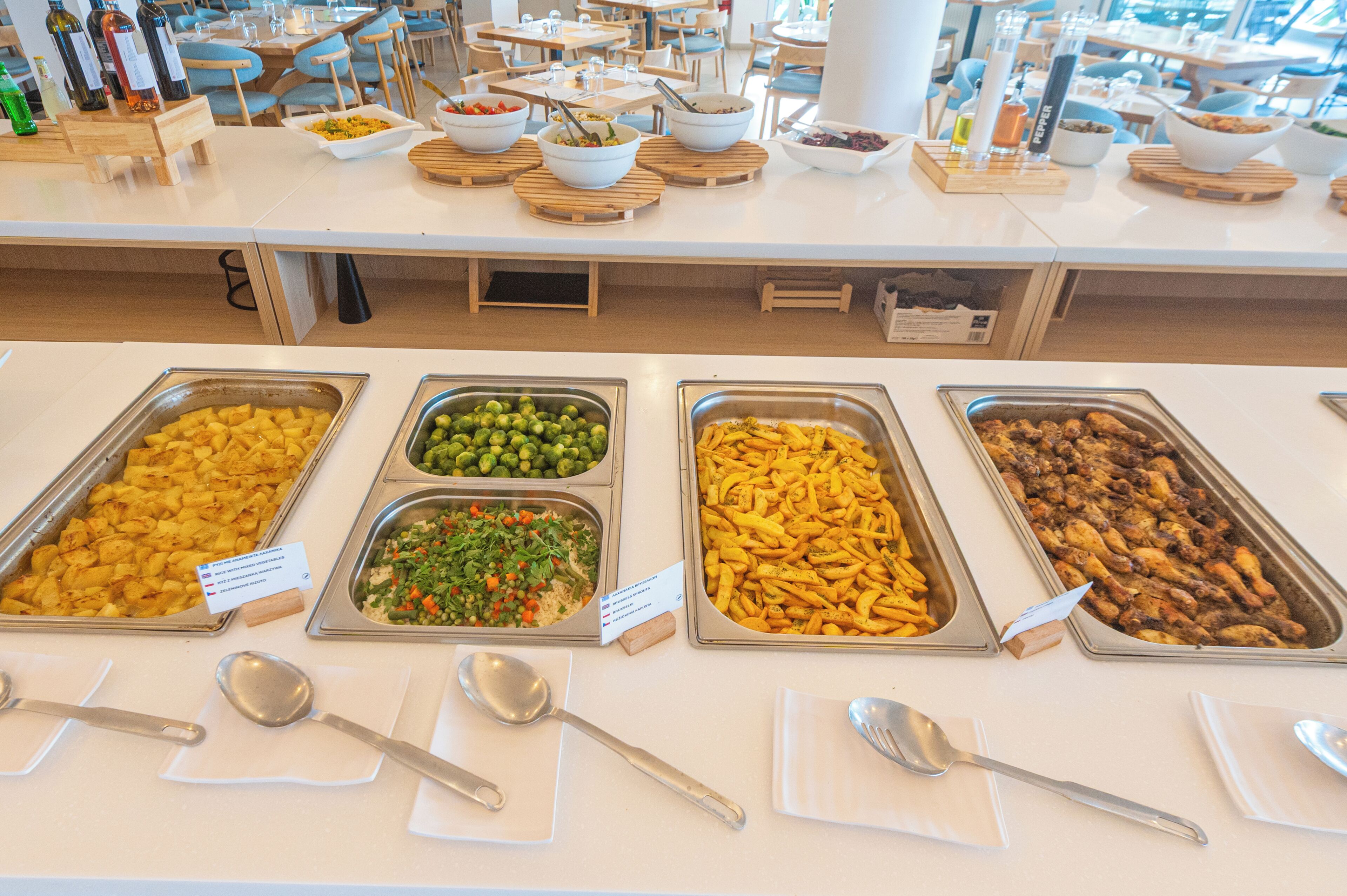 A buffet with various food options including potatoes, mixed vegetables, and chicken wings.