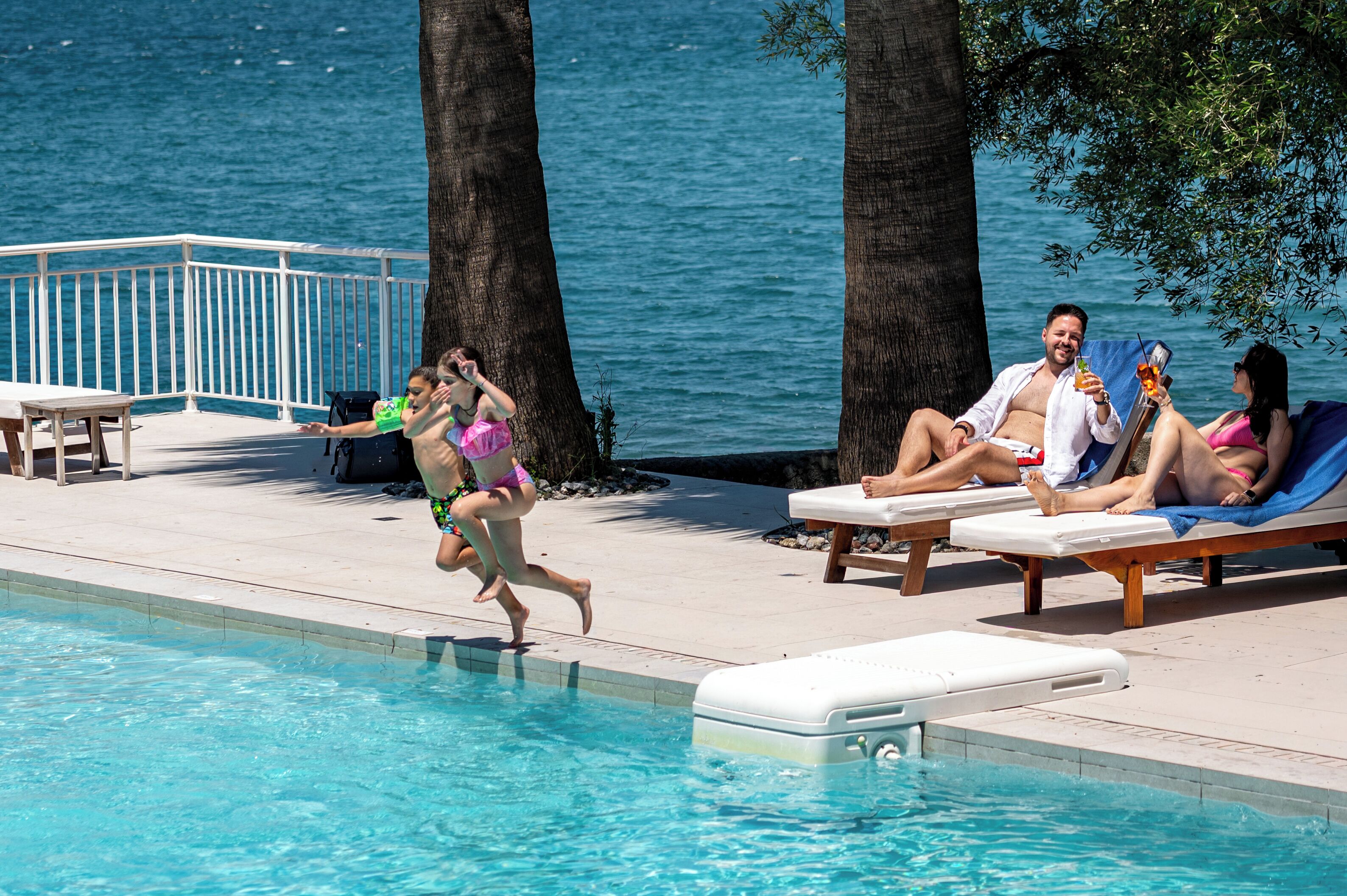Un espace aménagé au bord de la piscine, avec des chaises longues, une piscine et une vue sur la mer.