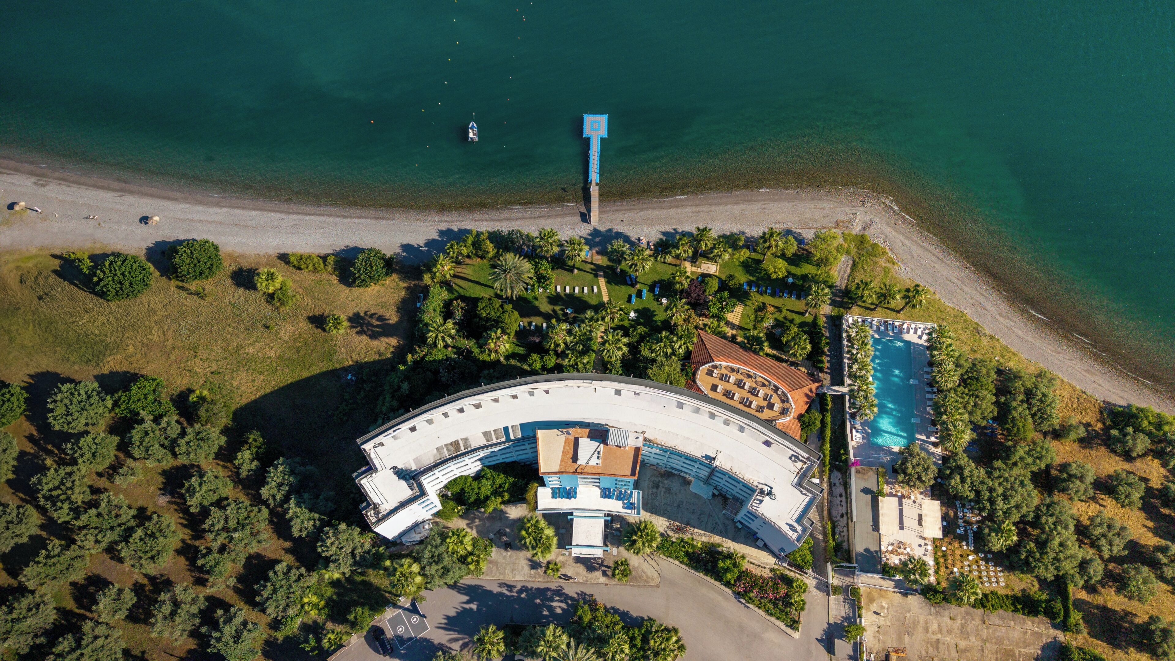 Vista aérea de un resort con piscina, playa y exuberante vegetación.