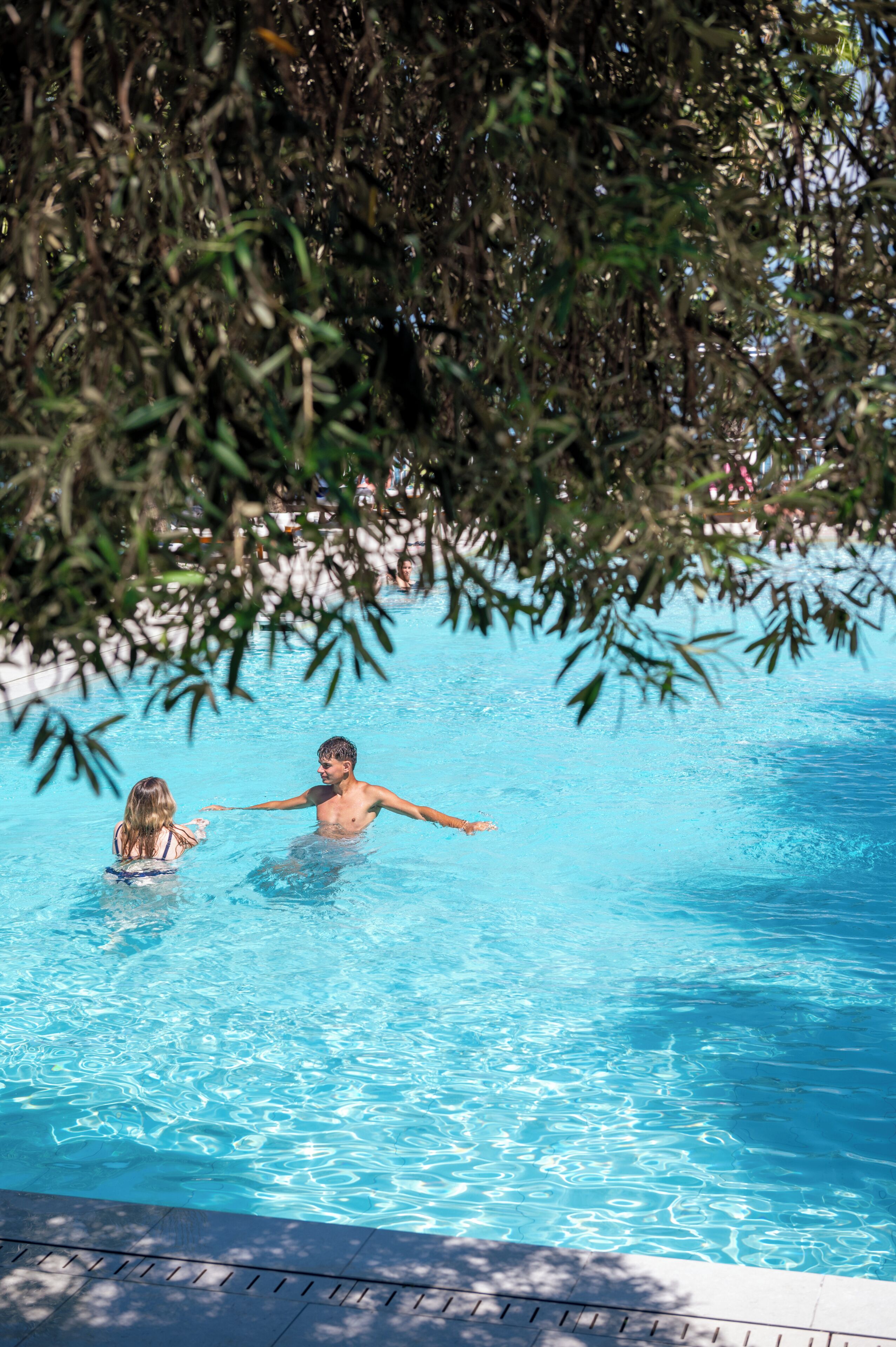 Una piscina con agua cristalina y borde de azulejos.