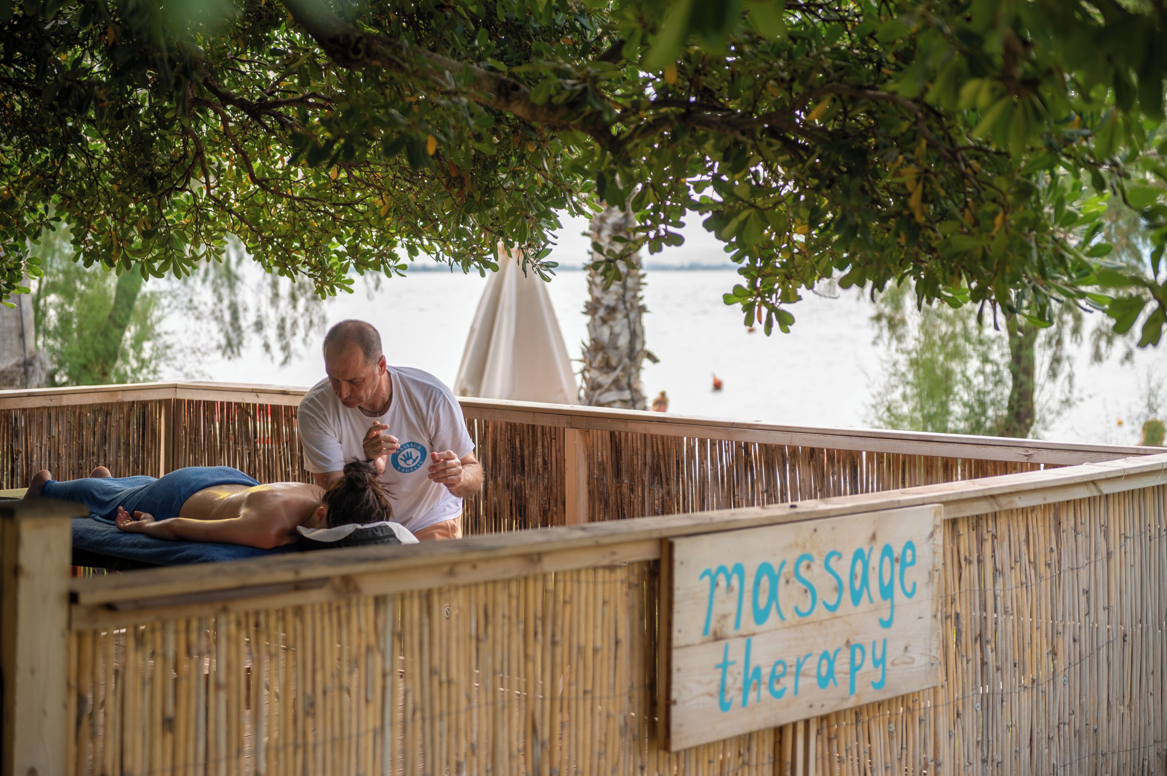A wooden structure labeled 'massage therapy' with a person lying on a mat receiving a massage.