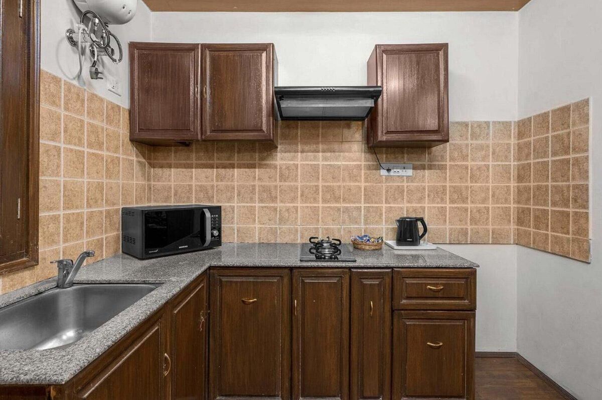 Een keuken met houten kastjes, een magnetron, een koffiezetapparaat en een spoelbak.
