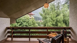 A balcony with a wooden bench, a table with a glass, and a hanging light fixture. - The Bear Creek Homestay Manali (Manali)
