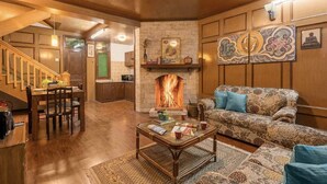 A cozy living room with a fireplace, wooden furniture, and artwork on the walls. - The Bear Creek Homestay Manali (Manali)