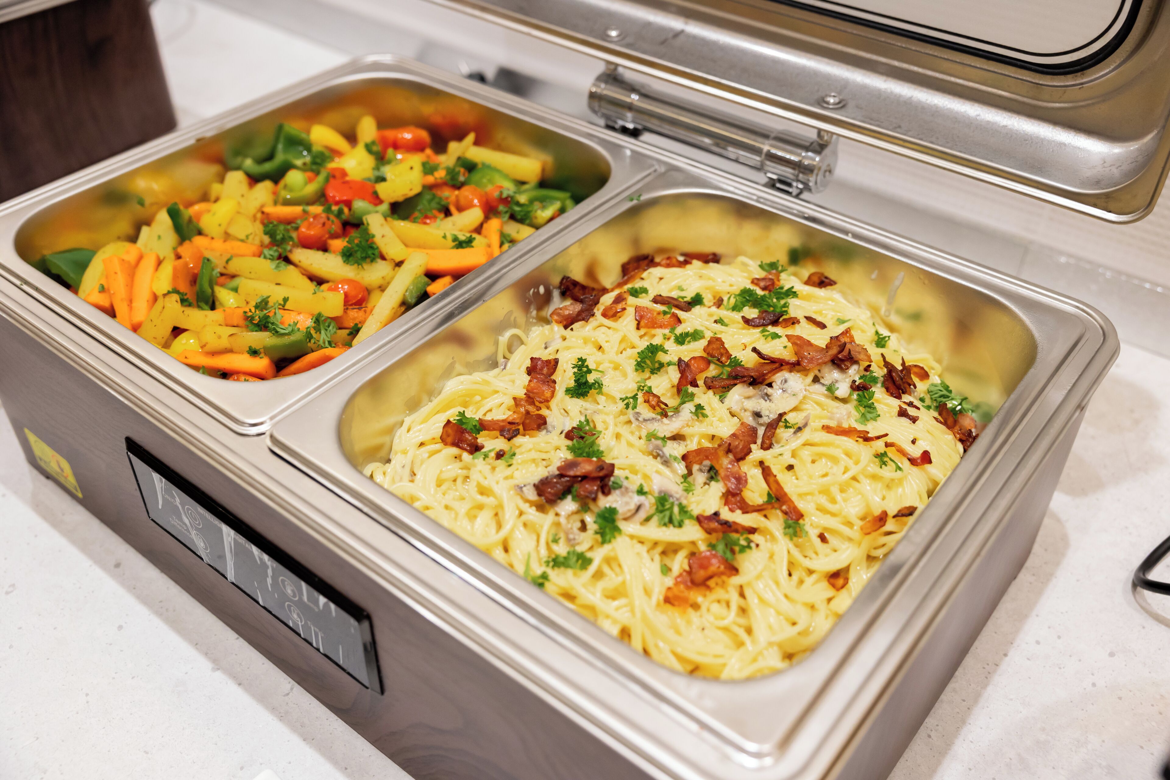 En buffet med pasta og en grøntsagsret.