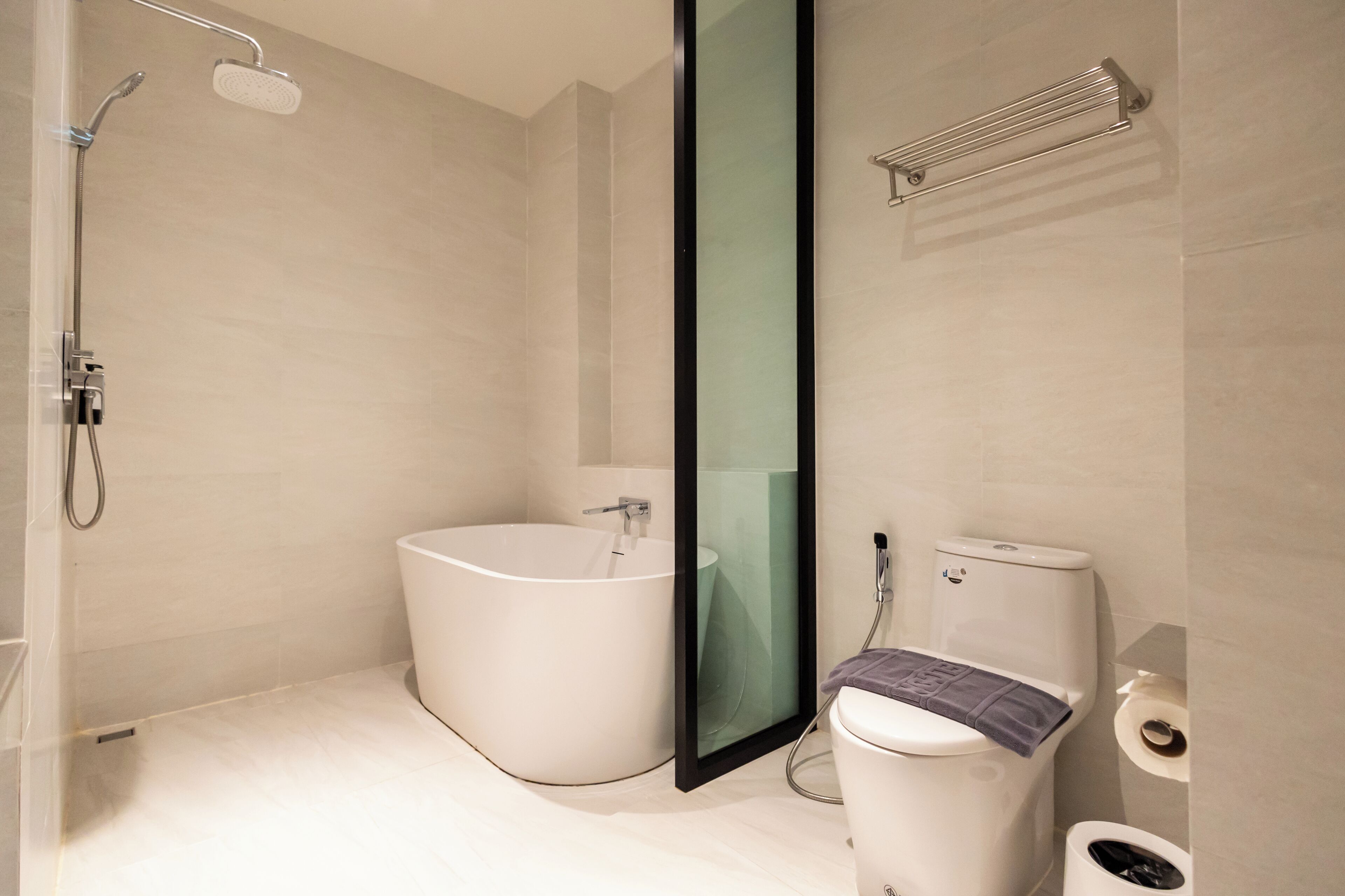Une salle de bain moderne avec une baignoire sur pieds, une douche à parois de verre et des toilettes sur lesquelles est posée une serviette.