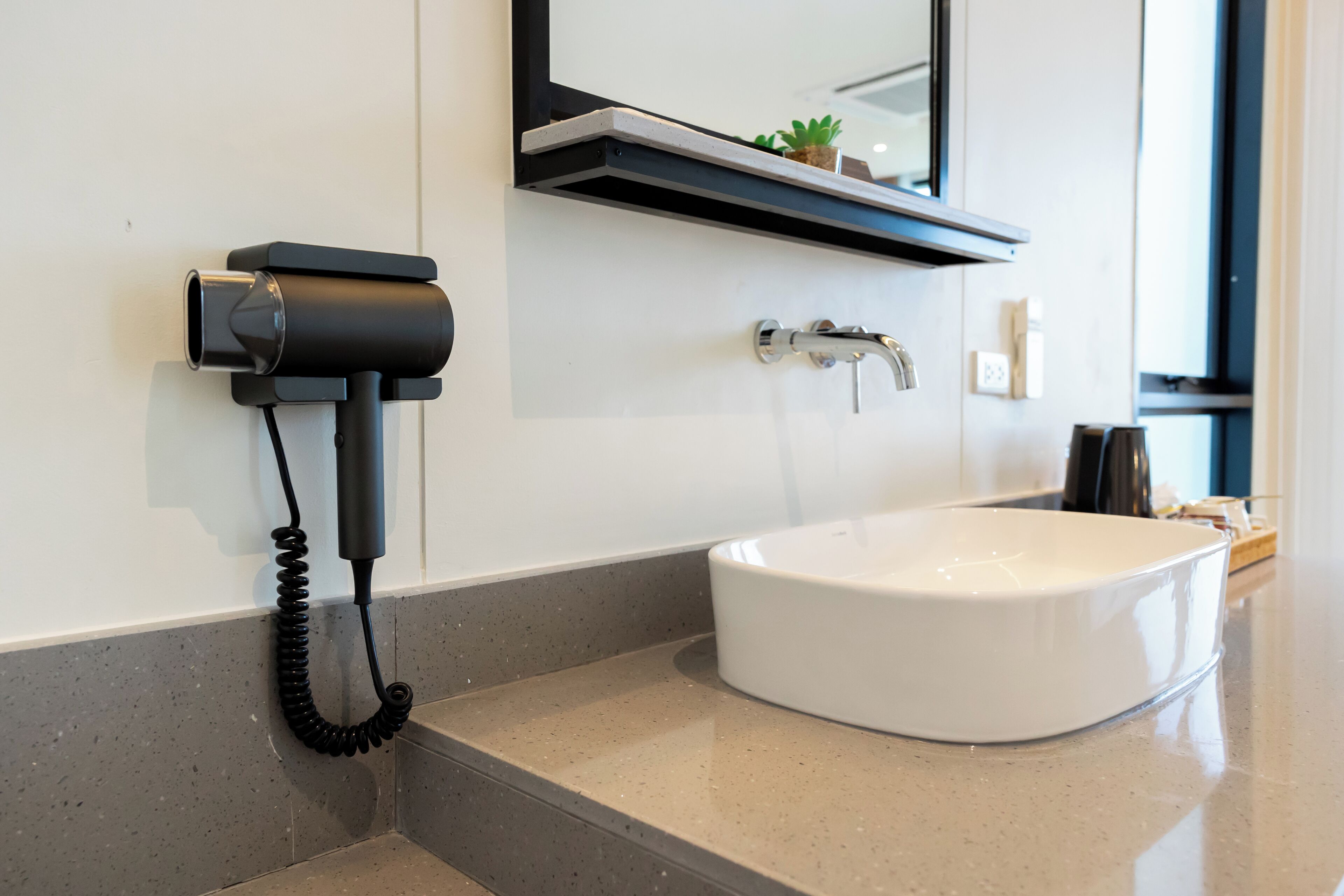 A bathroom with a white sink, a black telephone, and a mirror above the sink.