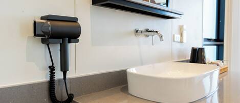 A bathroom with a white sink, a black telephone, and a mirror above the sink.
