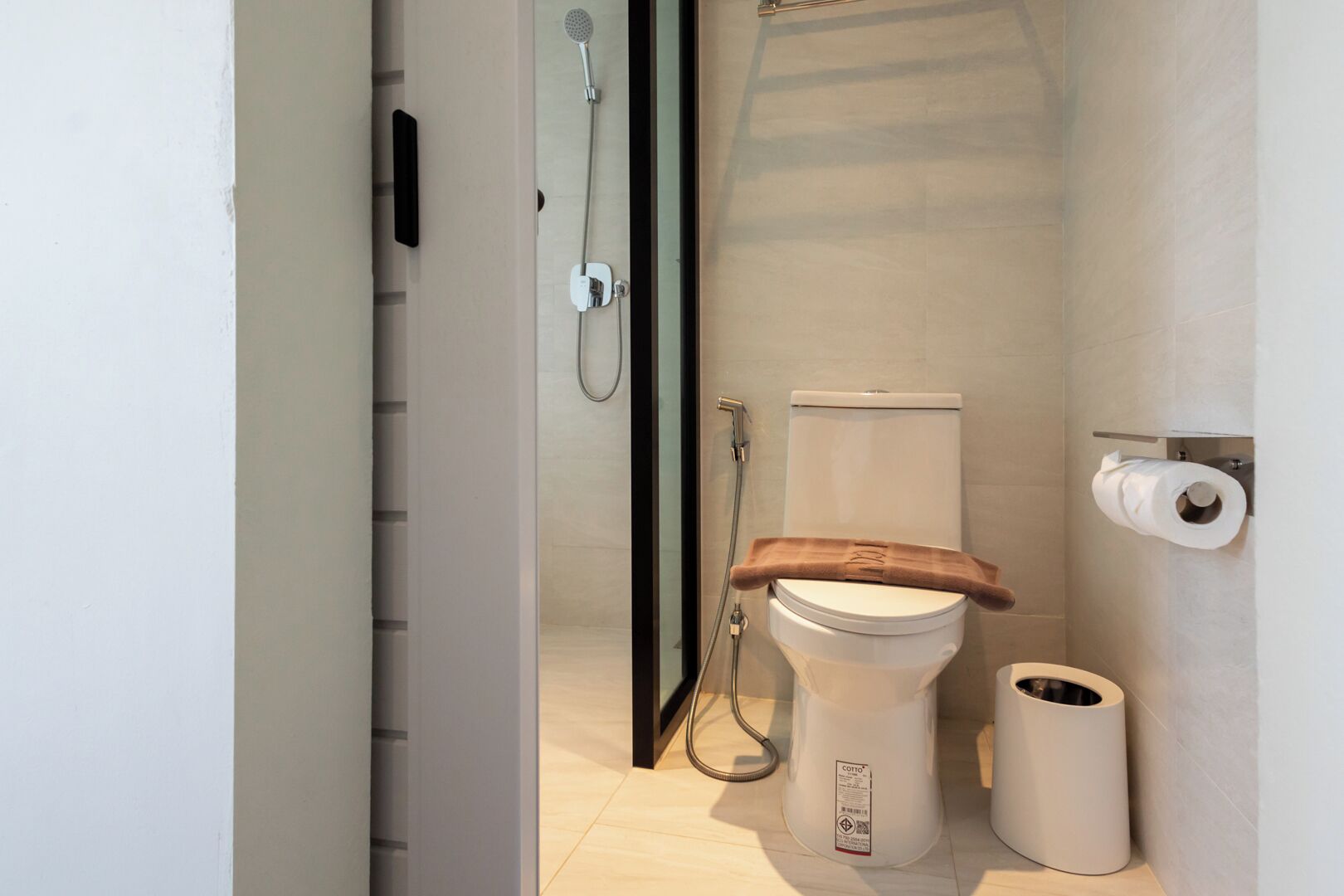 A modern bathroom with a toilet, shower, and toilet paper holder.