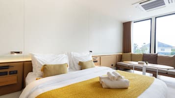 A hotel room with a large bed, a bedside table, a small table, and a sofa.