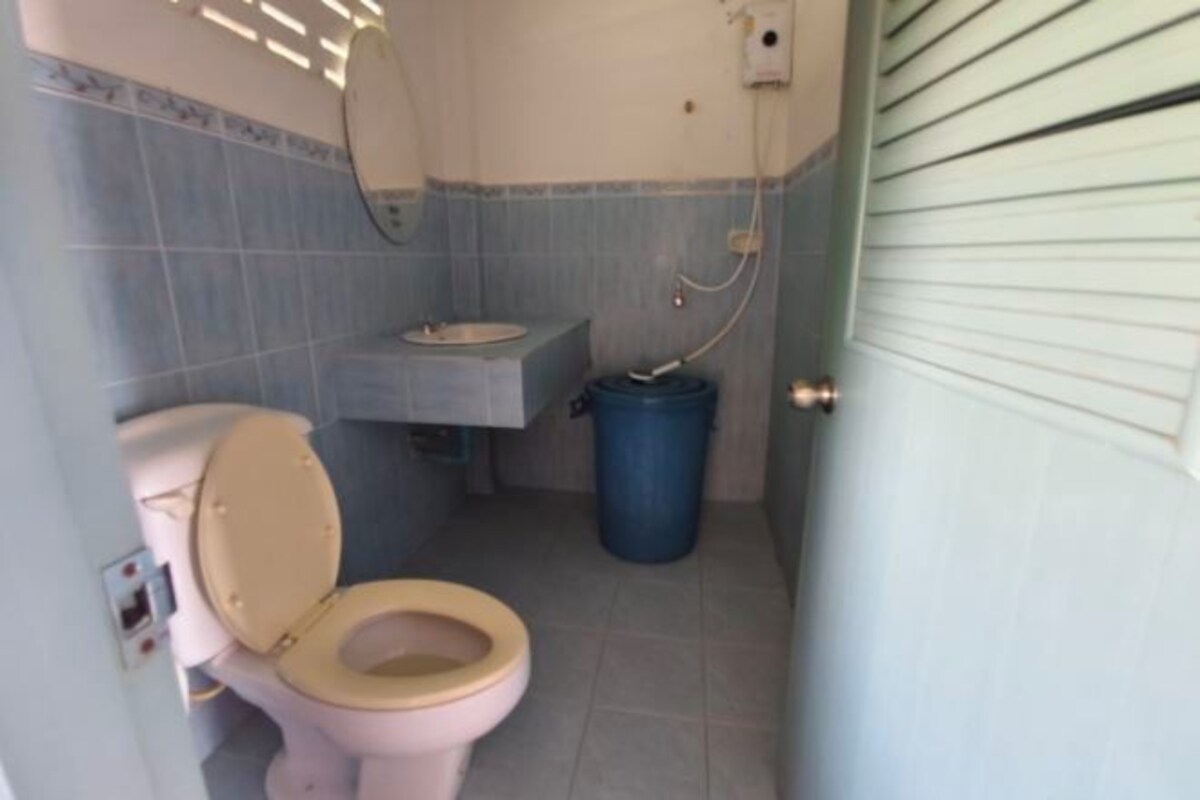 A small bathroom with a toilet, sink, and blue trash bin.