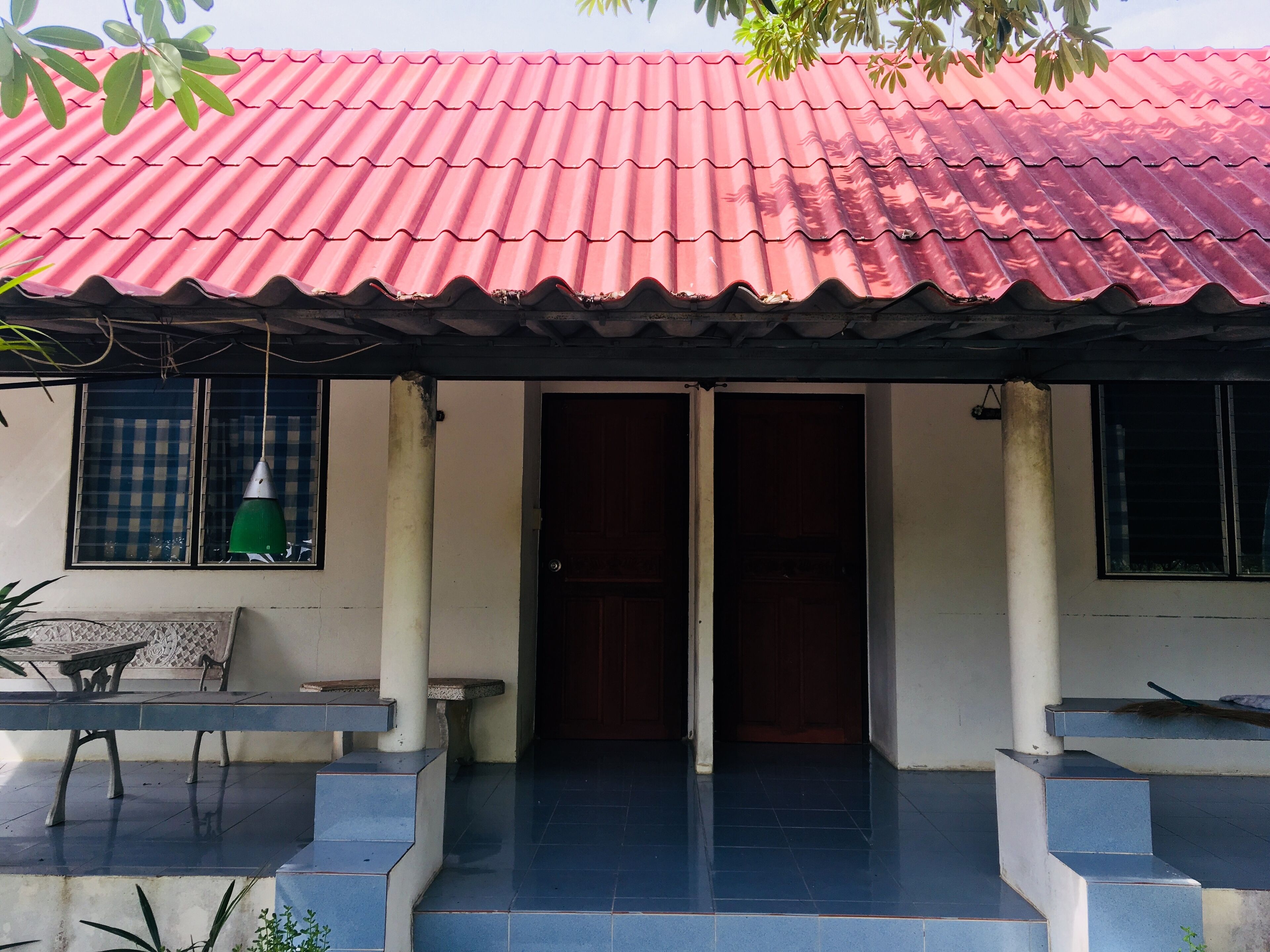 Ein Haus mit rotem Ziegeldach, einer Haustür und einer kleinen Veranda mit Treppen.